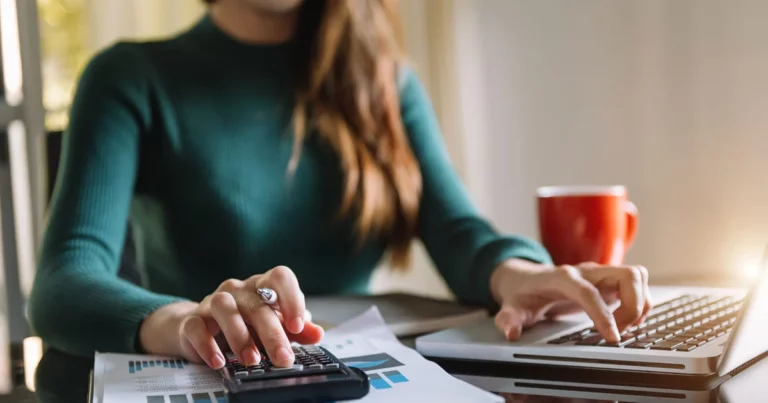 Dirigeant TPE PME gérant sa pré-comptabilité avec calculatrice et ordinateur